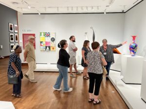 A variety of white people look at the glass sculptures described in the body of the story.