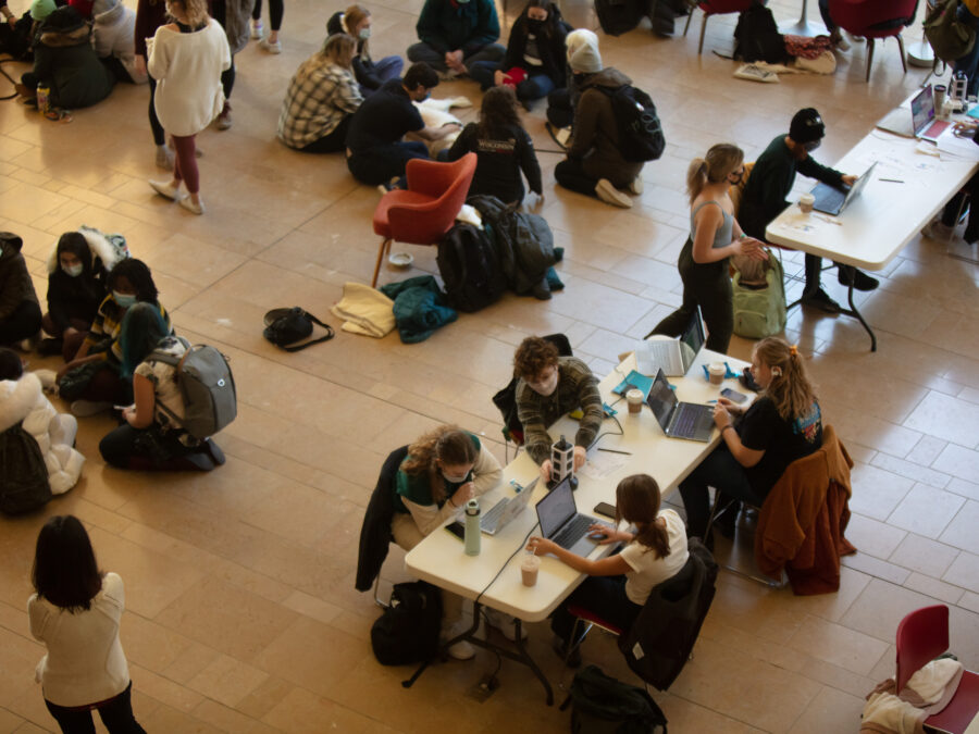 An overhead view of tables full of studying students on the right, and students gathered around therapy dogs on the left