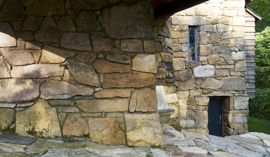 A very tall stone wall with a door and window in it